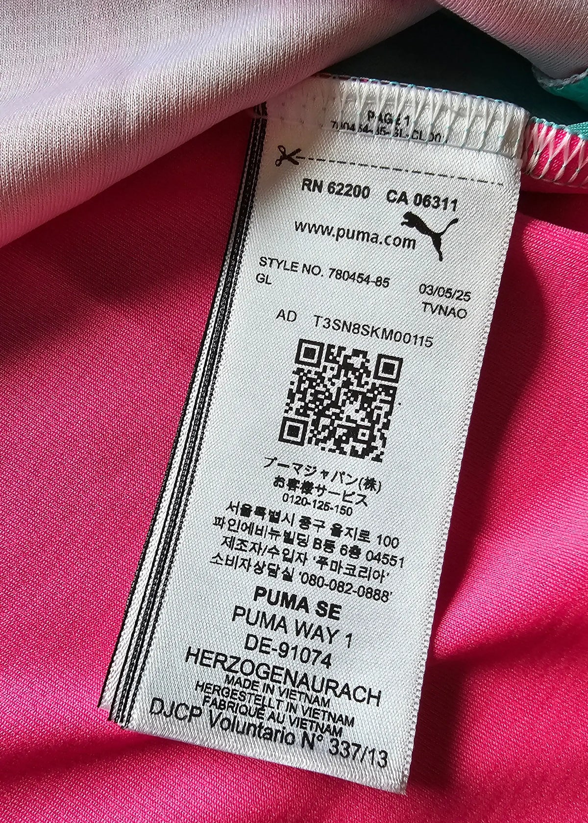 Close-up of a Puma care label on a pink Manchester City shirt, showing a QR code and the Puma SE address in Herzogenaurach.