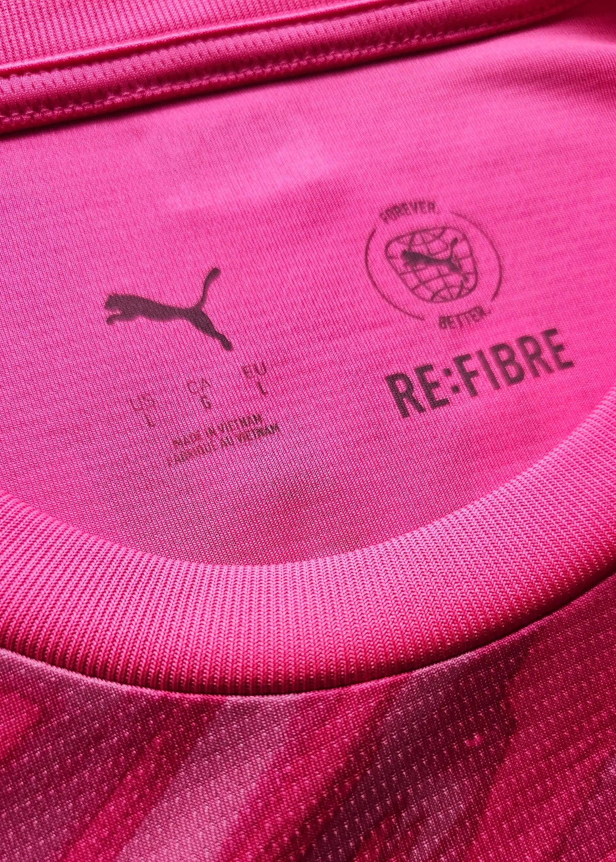 Interior neck view of a pink Manchester City shirt showing a Puma logo, a 'RE:FIBRE Forever Better' stamp, and a Made in Vietnam mark.