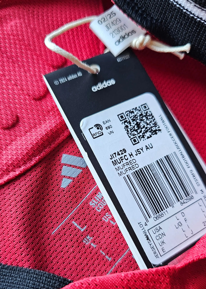 Tag detail showing adidas brand, MUFC H JSY AU, and size L with care instructions.