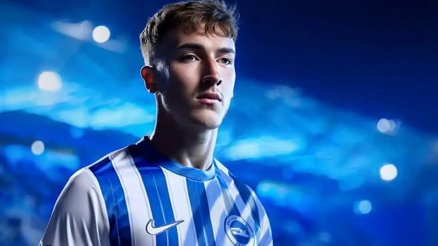 Jack Hinshelwood posed for Brighton & Hove Albion in a blue-and-white striped football shirt, bright stadium lights in the background.