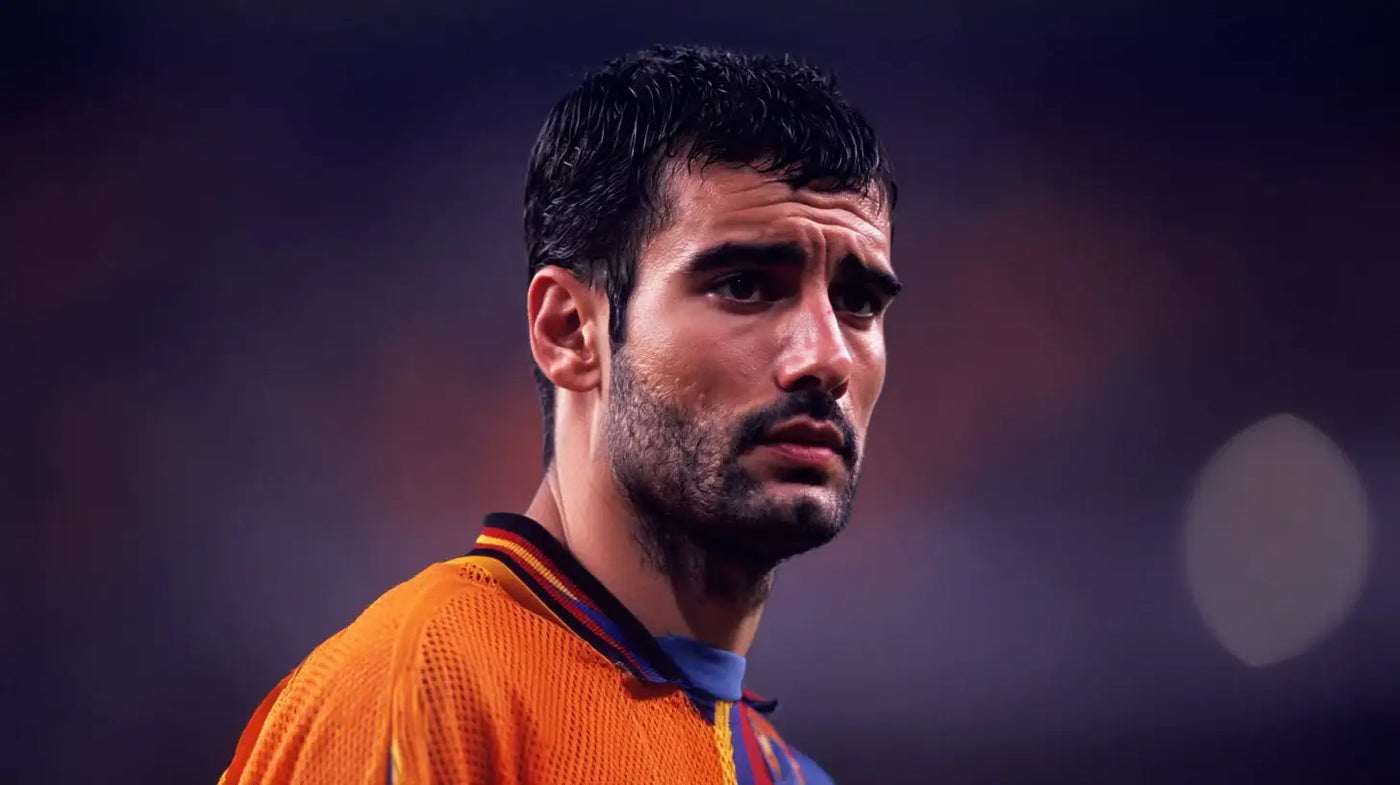 Josep Guardiola in a Barcelona 1992 orange football shirt with red and blue collar trim, looking to the side in a stadium setting.