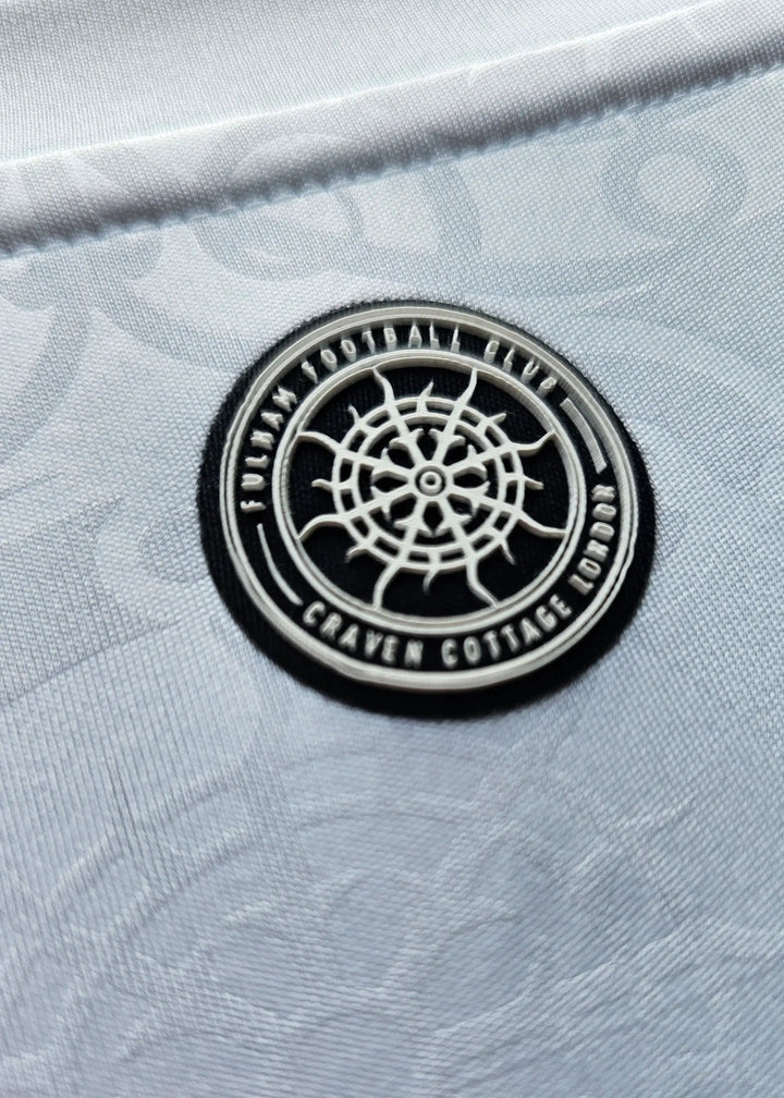 Close-up of the circular Fulham Football Club Craven Cottage London crest patch on white fabric, Josh King's Fulham F.C. 2025-2026 shirt.
