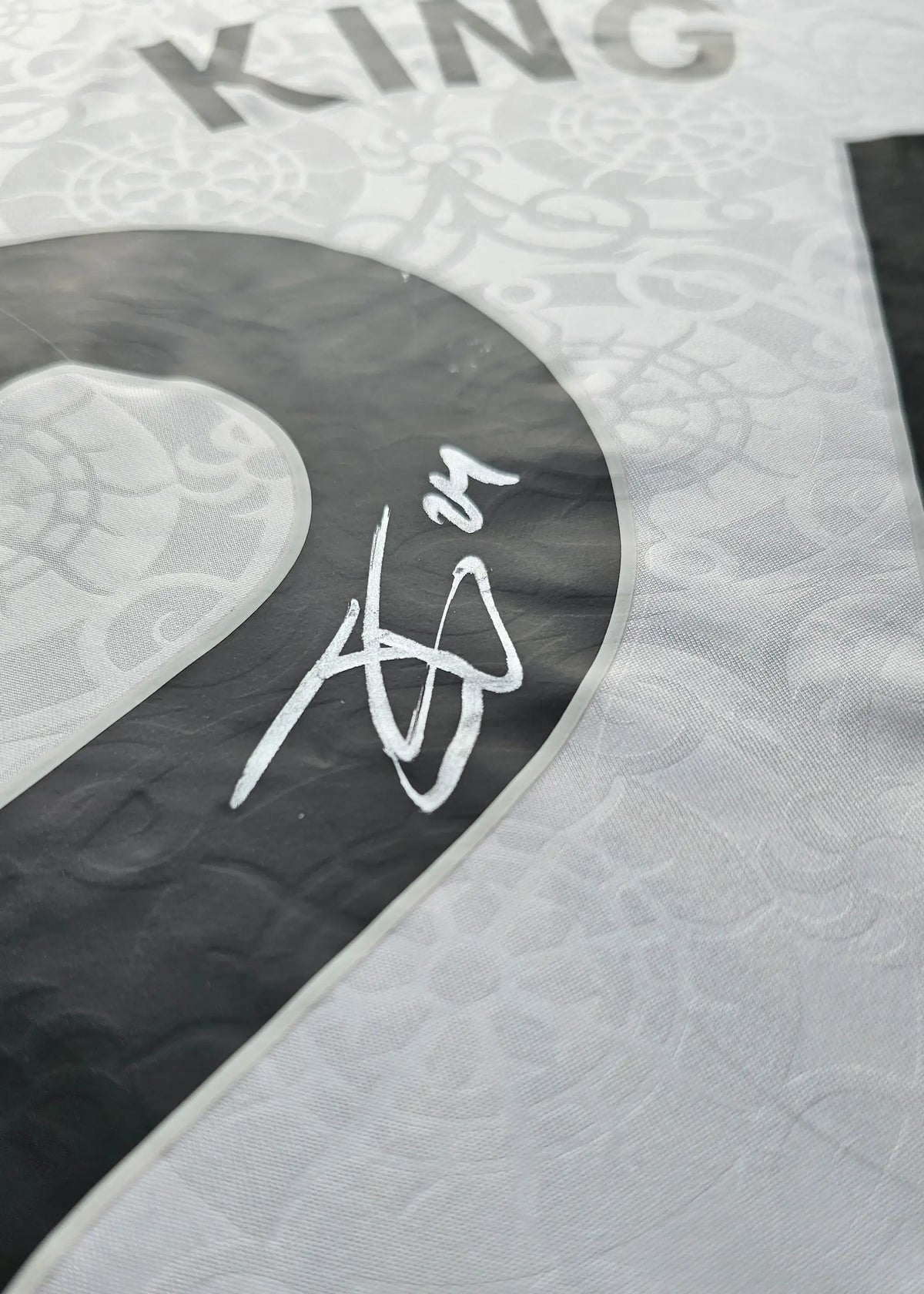 Close-up of a silver-marker signature over white tonal jacquard fabric, from Josh King's signed Fulham F.C. 2025-2026 No. 24 shirt.