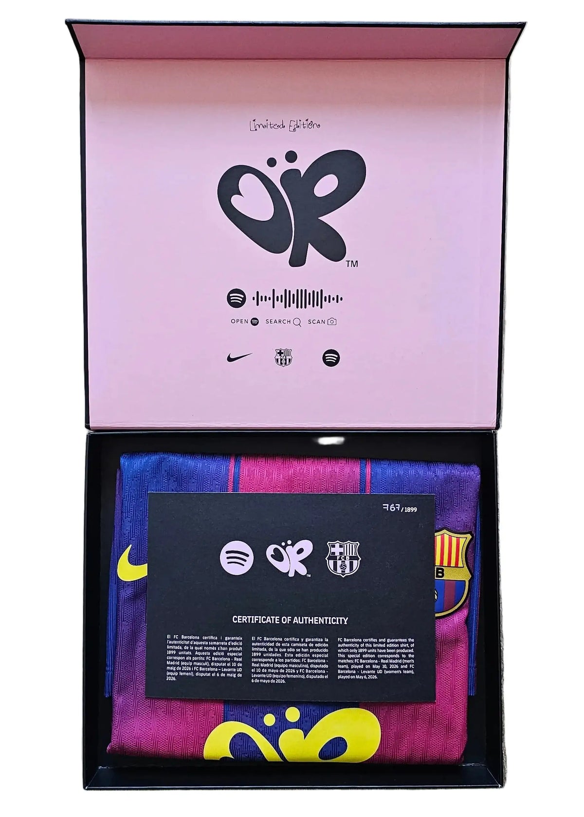 An open presentation box, containing a folded multicolor striped soccer jersey with yellow and blue accents, a black authenticity card, and branded packaging with a pink interior.
