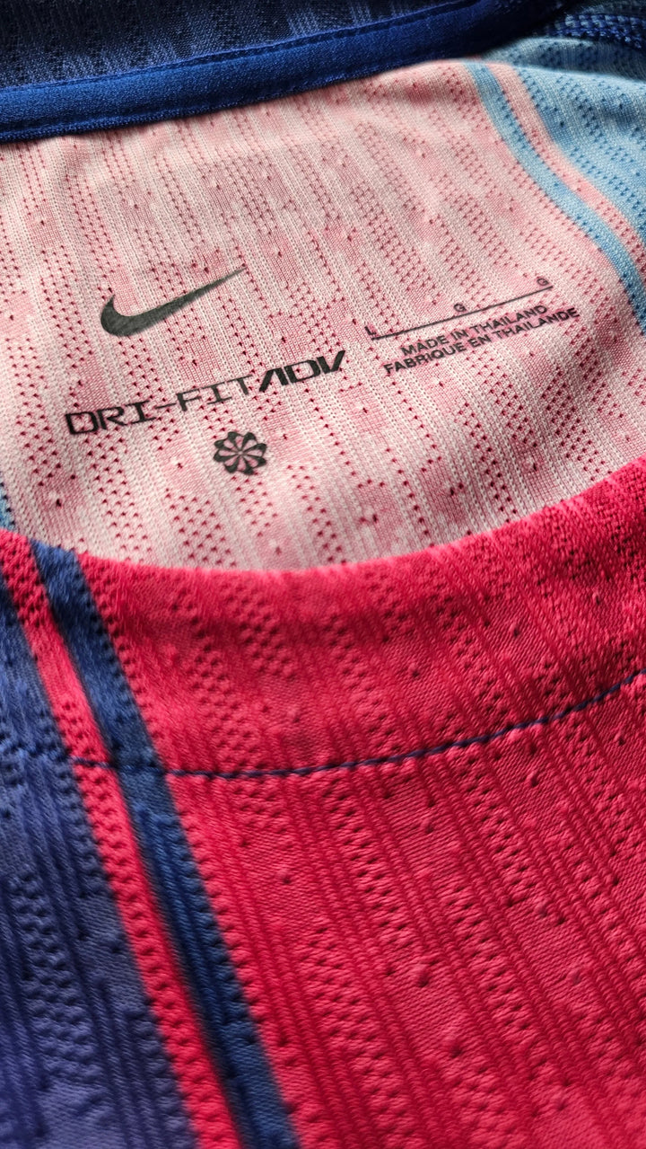 Close-up of a Nike athletic shirt showing the inner collar with a pink textured fabric, navy blue trim, and a red knit section. The inside label reads ORI-FIT/ADV and shows the Nike swoosh.