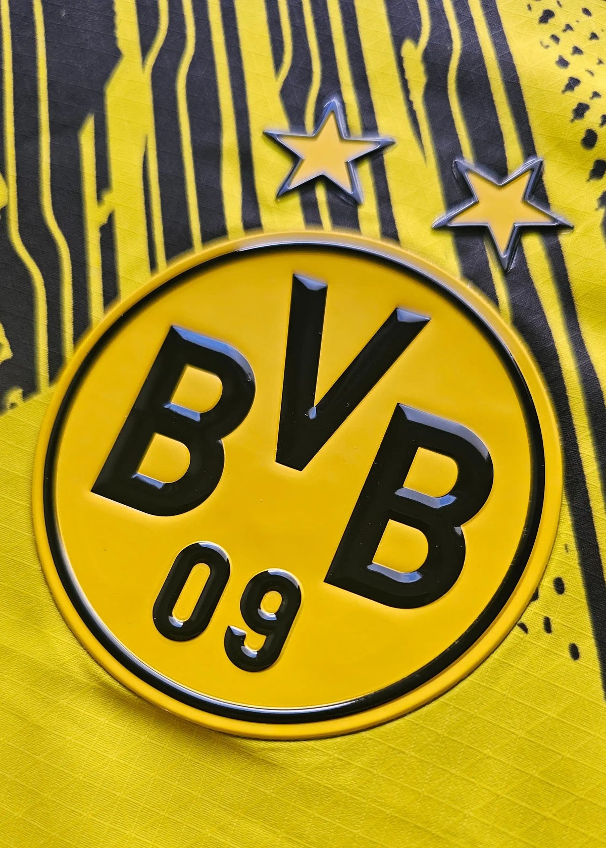 Detail of the Borussia Dortmund crest with two stars and 'BVB 09' text in black on yellow background.