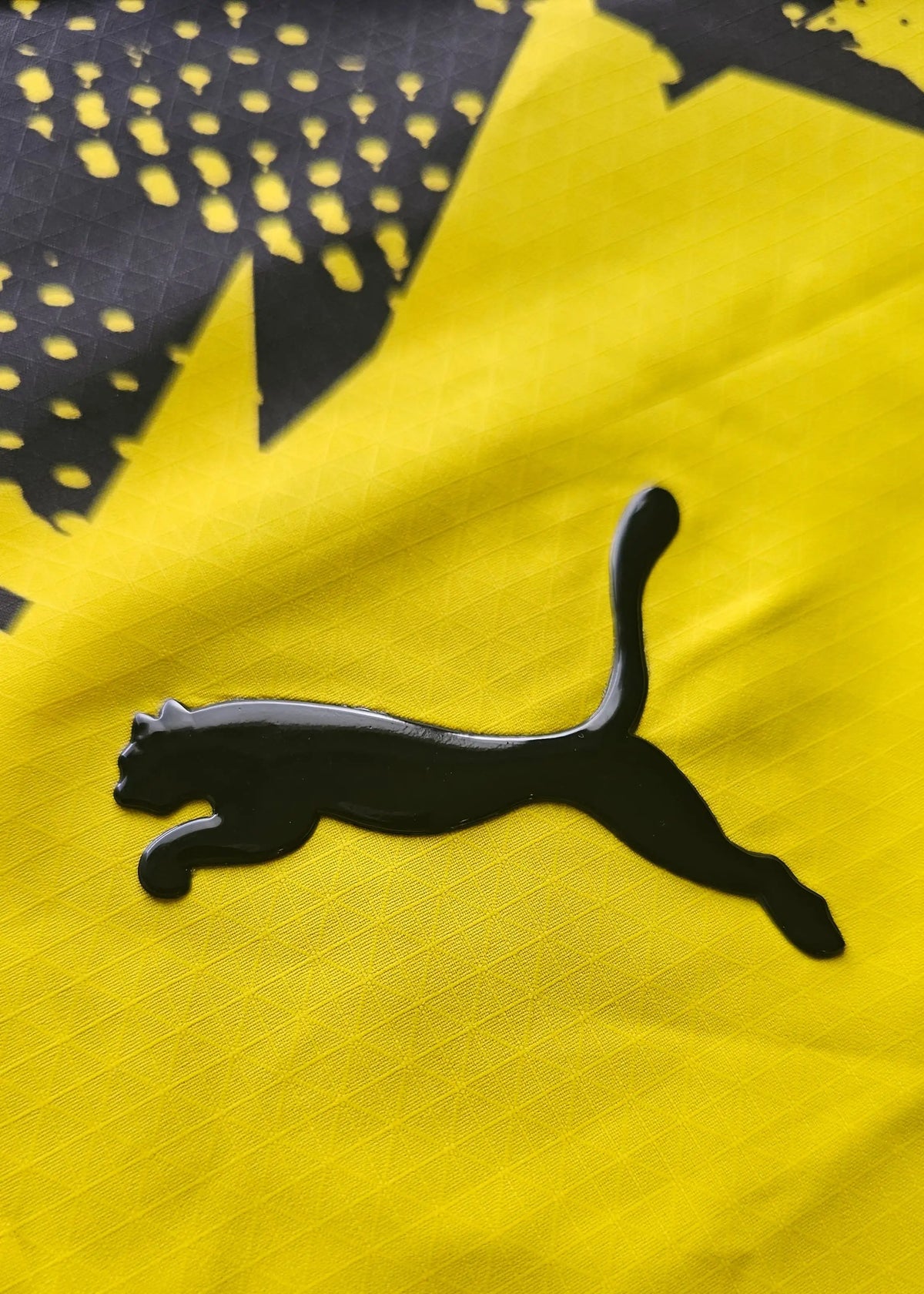 The black Puma cat logo stands out against the yellow fabric and its black jagged star-burst graphic pattern.