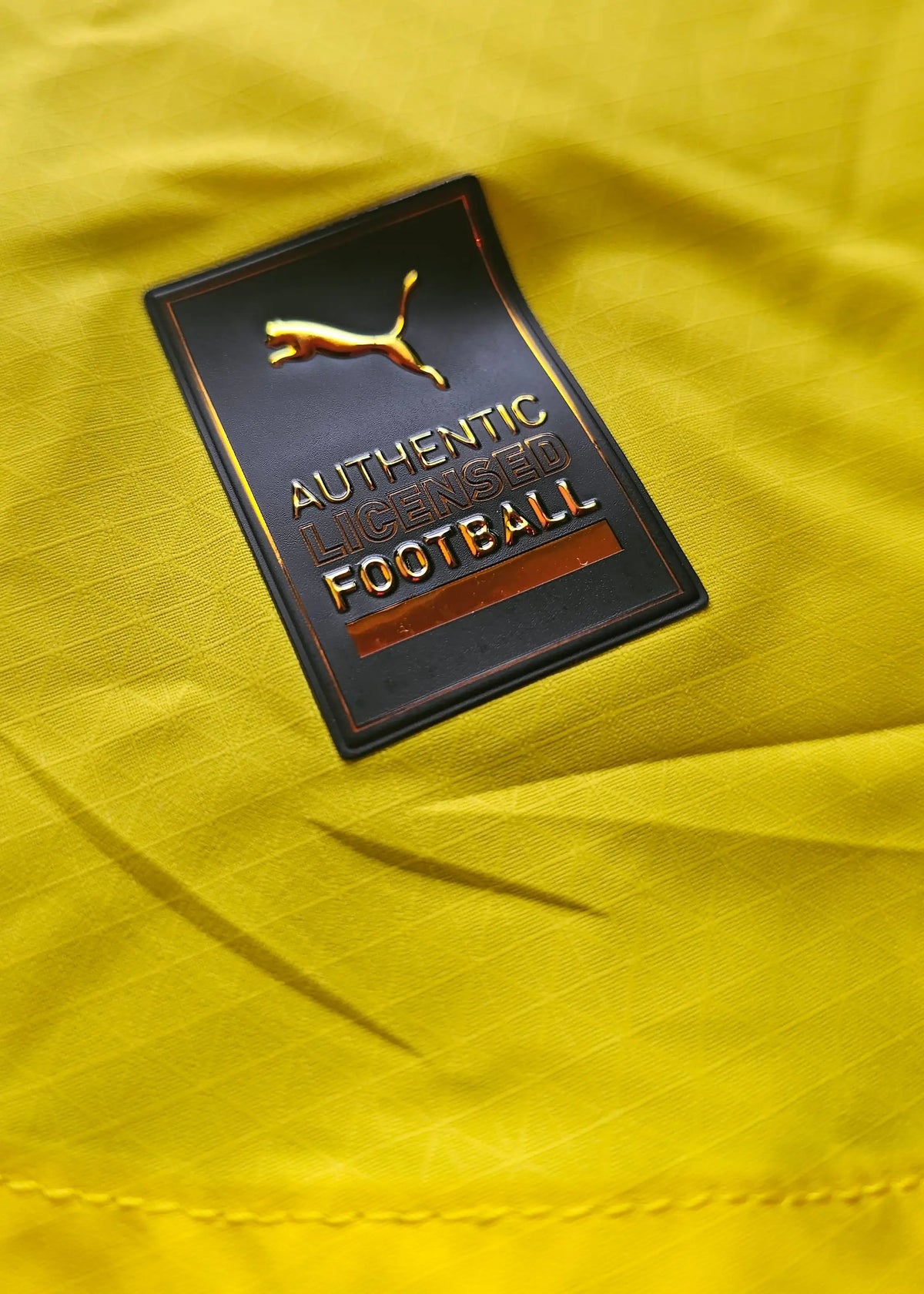 Crest detail showing Puma branding with "AUTHENTIC LICENSED FOOTBALL" text on a yellow background.