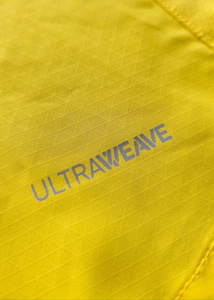 A macro shot of the yellow ripstop fabric shows the grey ULTRAWEAVE performance-fabric print near a seam.