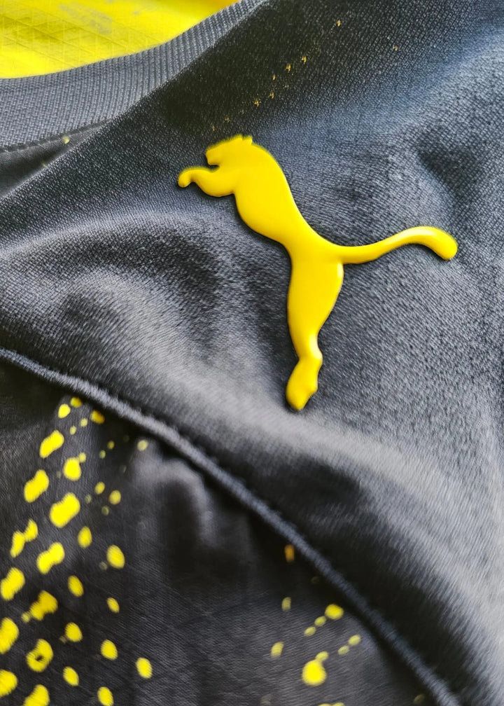 A yellow Puma cat logo is stitched onto the dark grey underside of the Borussia Dortmund shirt's collar.