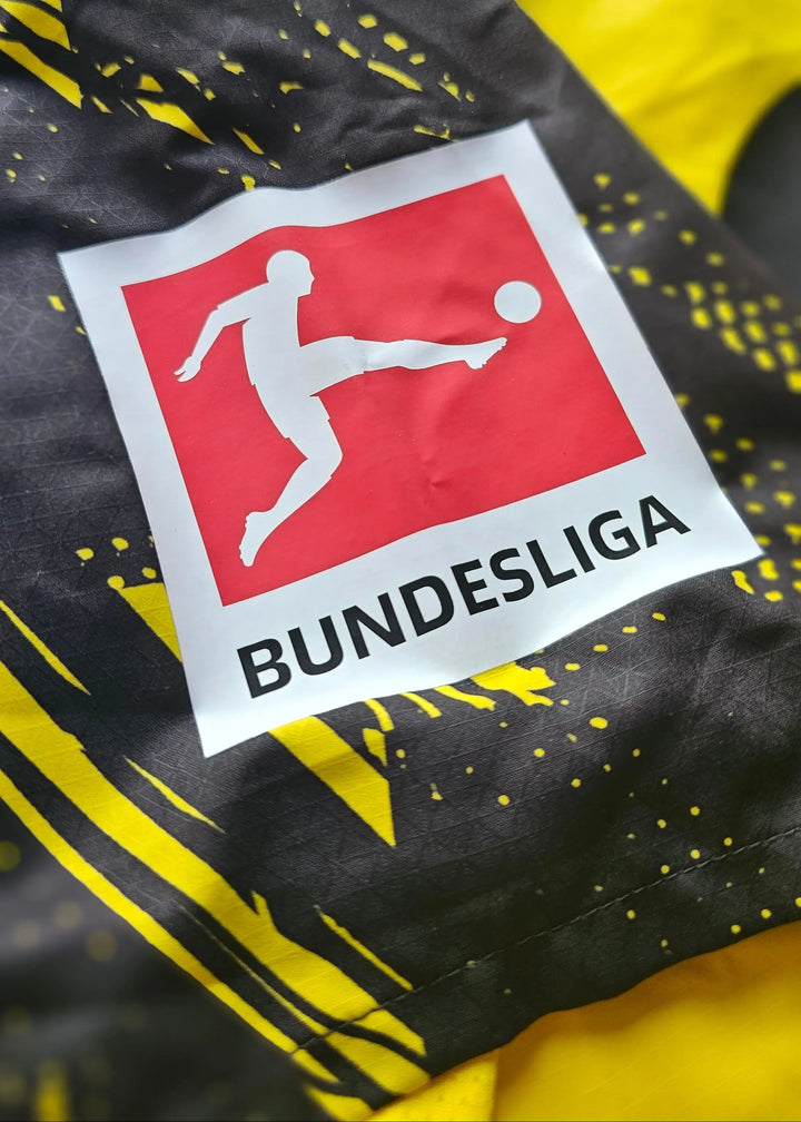 The red and white Bundesliga sleeve patch sits on the Borussia Dortmund shirt's black and yellow striped fabric.