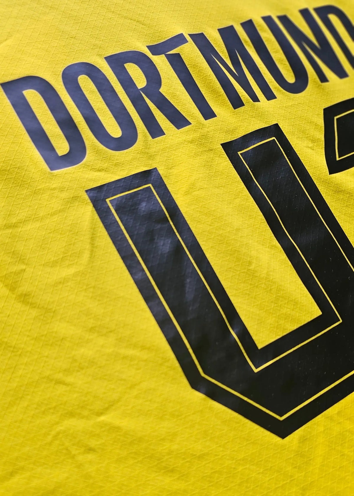 The DORTMUND nameplate arches in grey above the No. 41 printed in black on the shirt's yellow back panel.