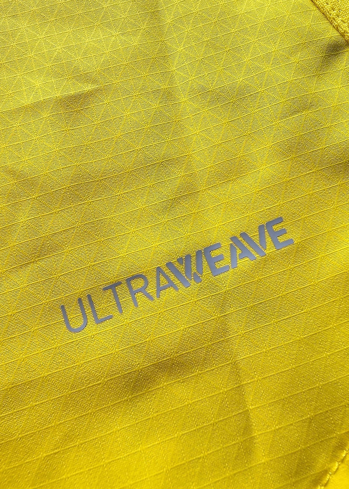 A macro shot of the yellow ripstop fabric shows the grey ULTRAWEAVE performance-fabric branding near a seam line.