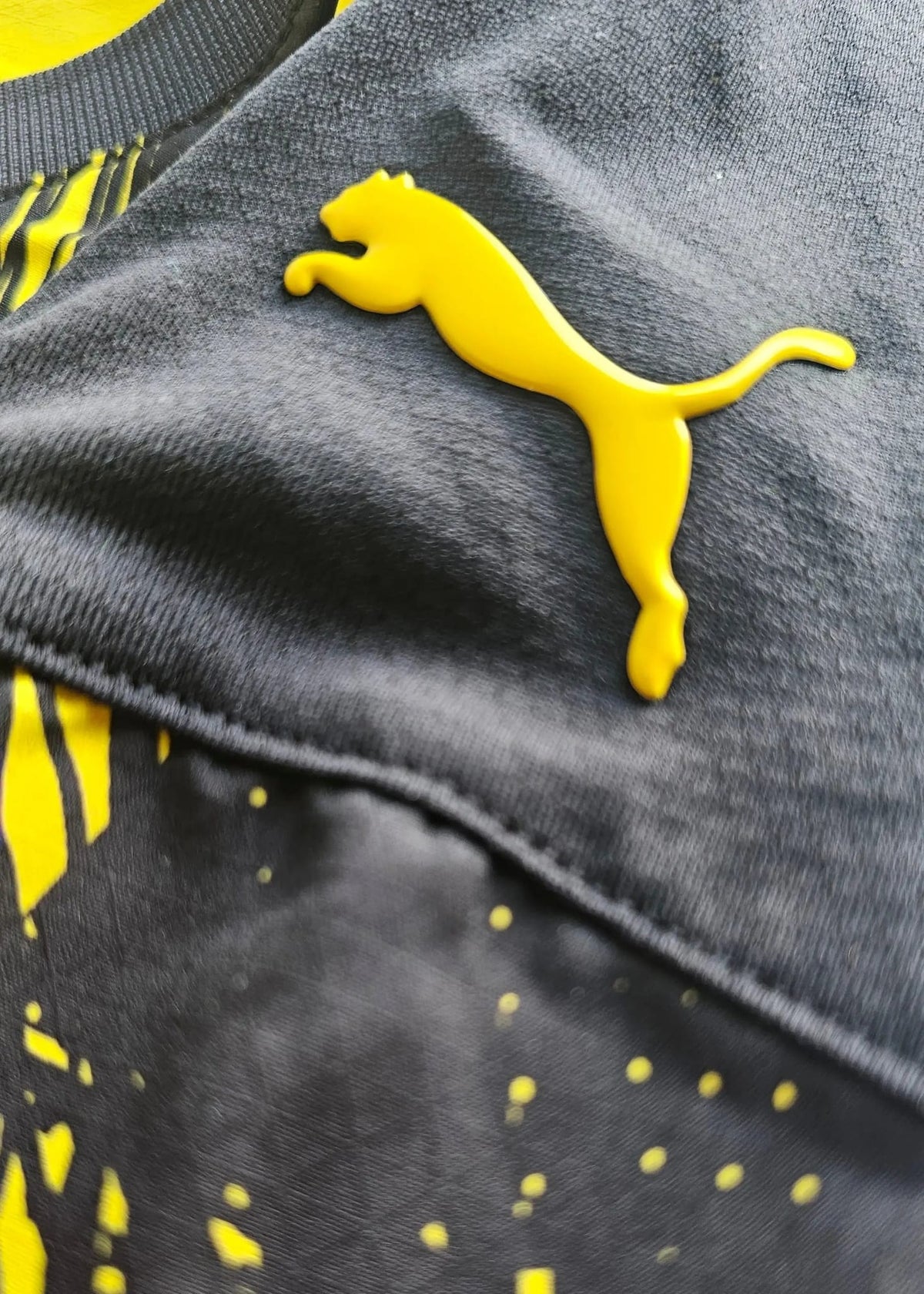 A yellow Puma cat logo is stitched onto the dark grey underside near the Borussia Dortmund shirt's collar.