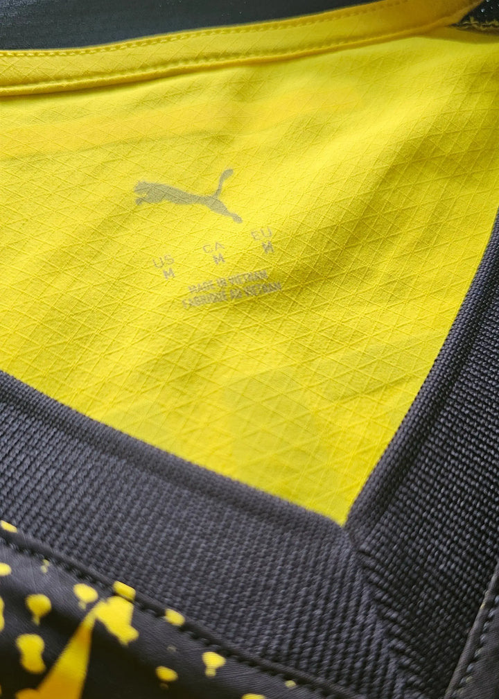 Inside the collar, a grey Puma cat logo sits above the size M and Made in Vietnam care print on yellow fabric.