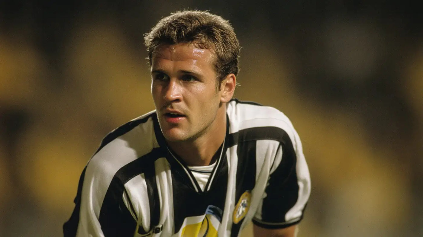 Oliver Bierhoff of Udinese leans forward watching the play while wearing a black and white striped football shirt.