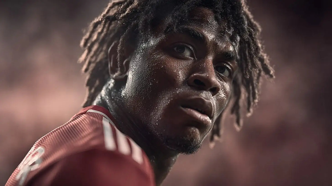 Patrick Dorgu in Manchester United home shirt looking back over his shoulder with sweat on his face.