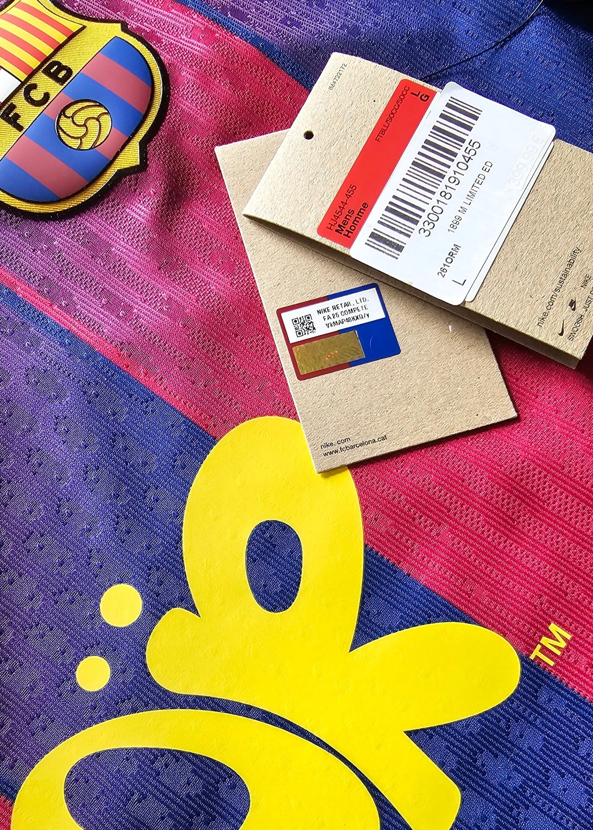 Nike swing tags, a QR-coded chip sticker, the Barcelona crest and a pink butterfly 'OR' logo, on the maroon and blue 2025-2026 shirt for Pau Cubarsi, No. 5.