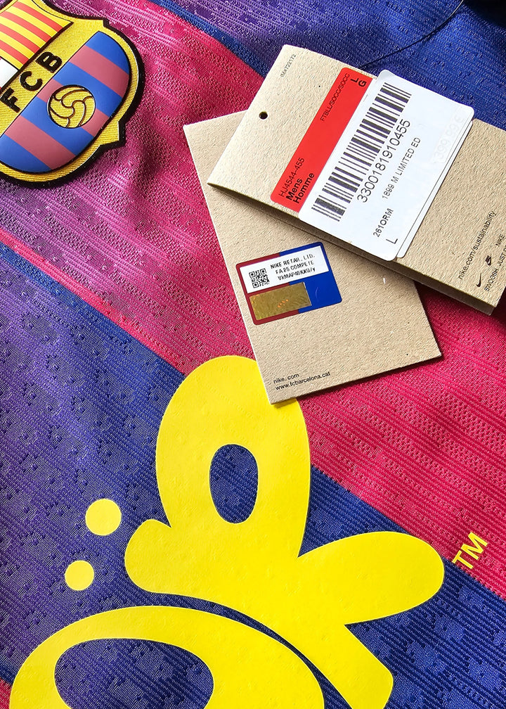 Nike swing tags, a QR-coded chip sticker, the Barcelona crest and a pink butterfly 'OR' logo, on the maroon and blue 2025-2026 shirt for Pau Cubarsi, No. 5.