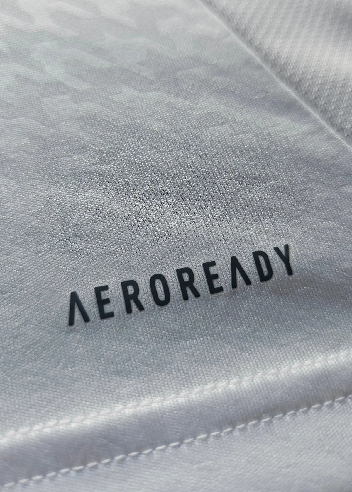 A macro shot of the AEROREADY performance tag printed onto the white underside of this Raul Asencio Real Madrid 2024-2025 shirt fabric.