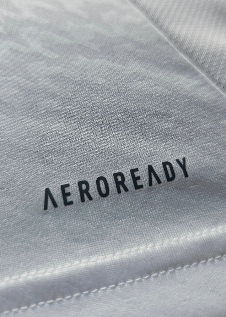 A macro shot of the AEROREADY performance tag printed onto the white underside of this Raul Asencio Real Madrid 2024-2025 shirt fabric.