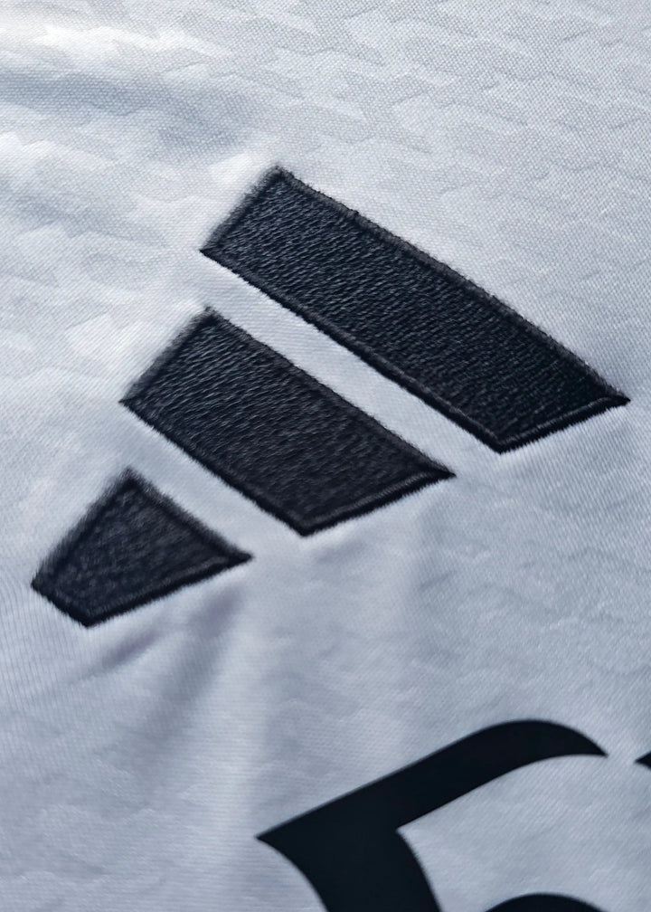 The adidas three-stripe logo on the shoulder seam of this Raul Asencio Real Madrid 2024-2025 No. 35 shirt, photographed in close-up.