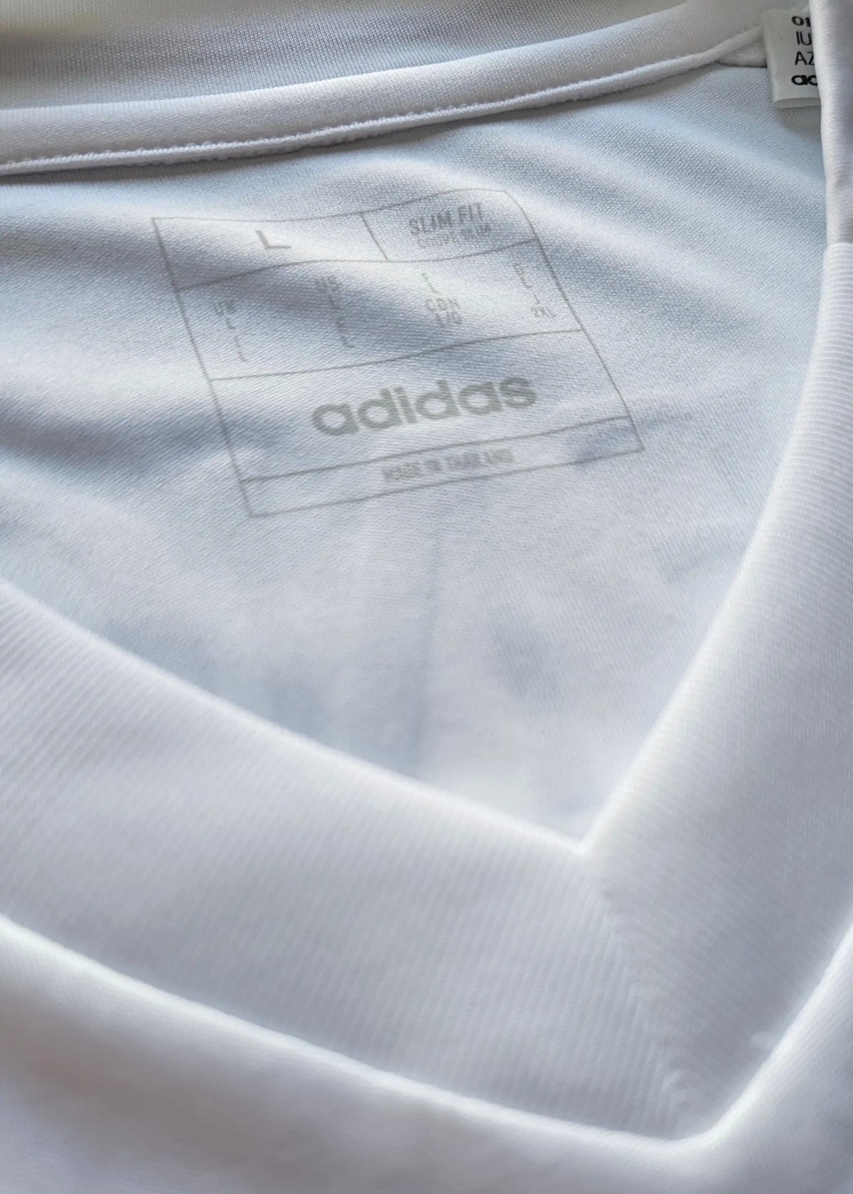 The inside collar label of this Raul Asencio Real Madrid 2024-2025 shirt shows size L, Slim Fit cut, and the adidas Made in Thailand tag.