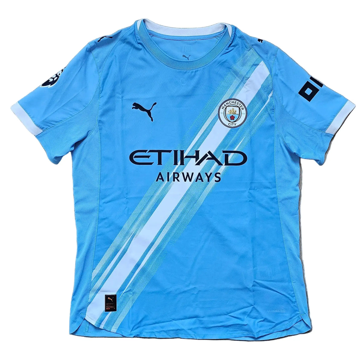 Front of a sky-blue Manchester City home shirt with the Etihad Airways sponsor and a Puma logo, from the signed Reigan Heskey Man City shirt.