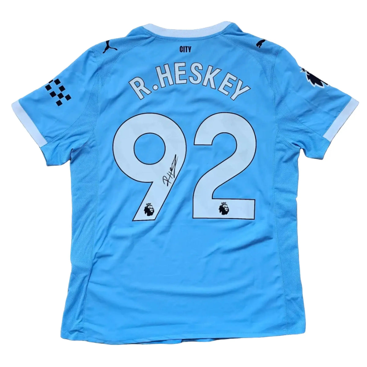 Back of a sky-blue Manchester City shirt with R.HESKEY and No. 92 above a signature, Reigan Heskey Manchester City F.C. 2025-2026, signed.