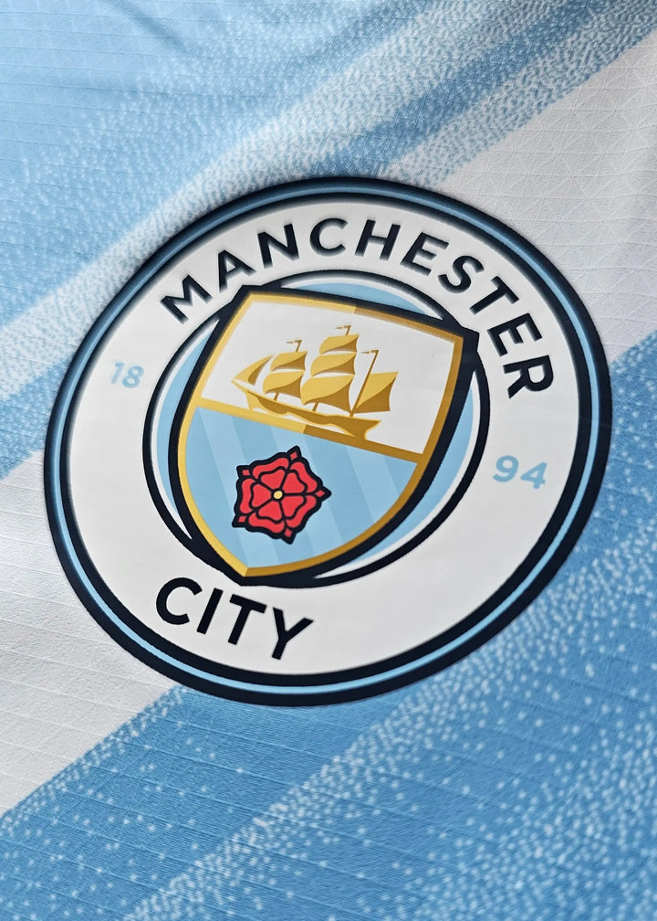 Crest detail featuring the Manchester City logo with a ship and red rose on a blue background.