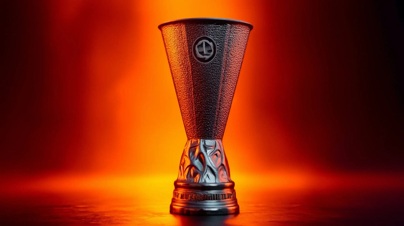 Full view of UEFA Europa League trophy lit by dramatic orange light on a dark stage.