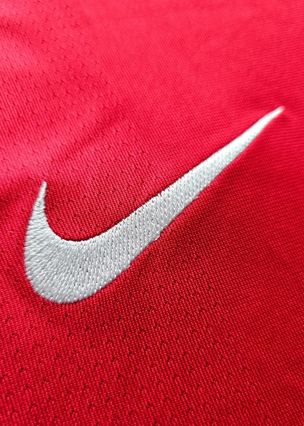 Close-up of the white embroidered Nike swoosh on the red chest, from Robin van Persie's signed Arsenal 2010-11 No. 10 shirt.