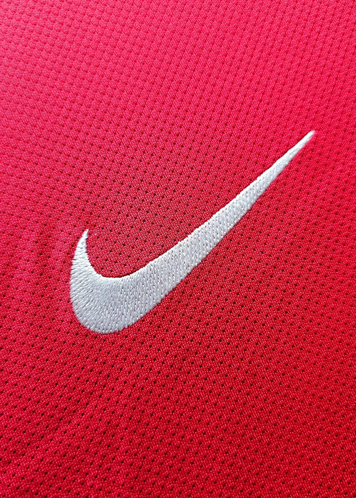 Close-up of the white Nike swoosh embroidered on red fabric, part of Robin van Persie's Arsenal 2011-12 No. 10 home shirt.