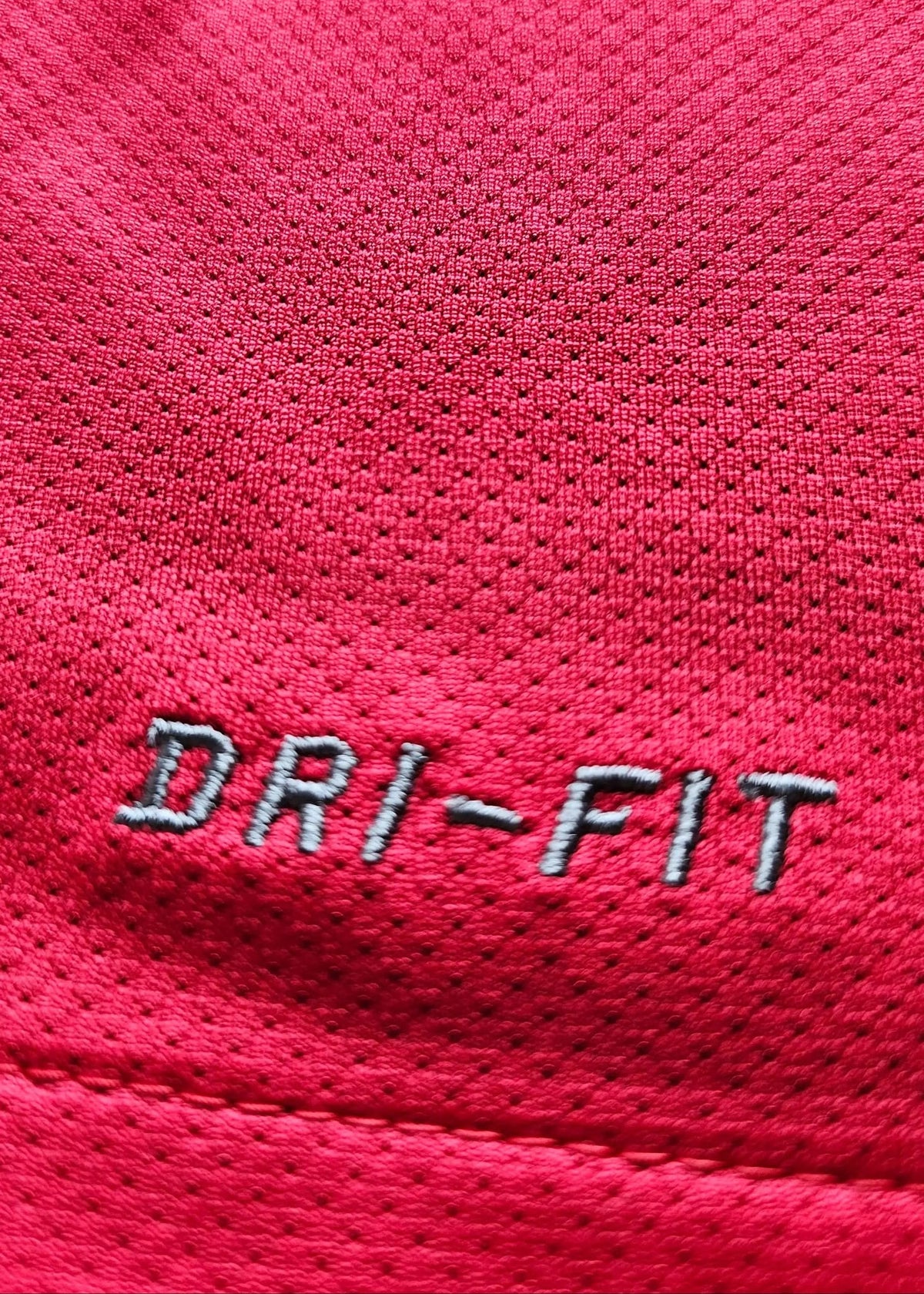 Close-up of the grey DRI-FIT logo embroidered on red fabric, part of Robin van Persie's Arsenal 2011-12 No. 10 home shirt.