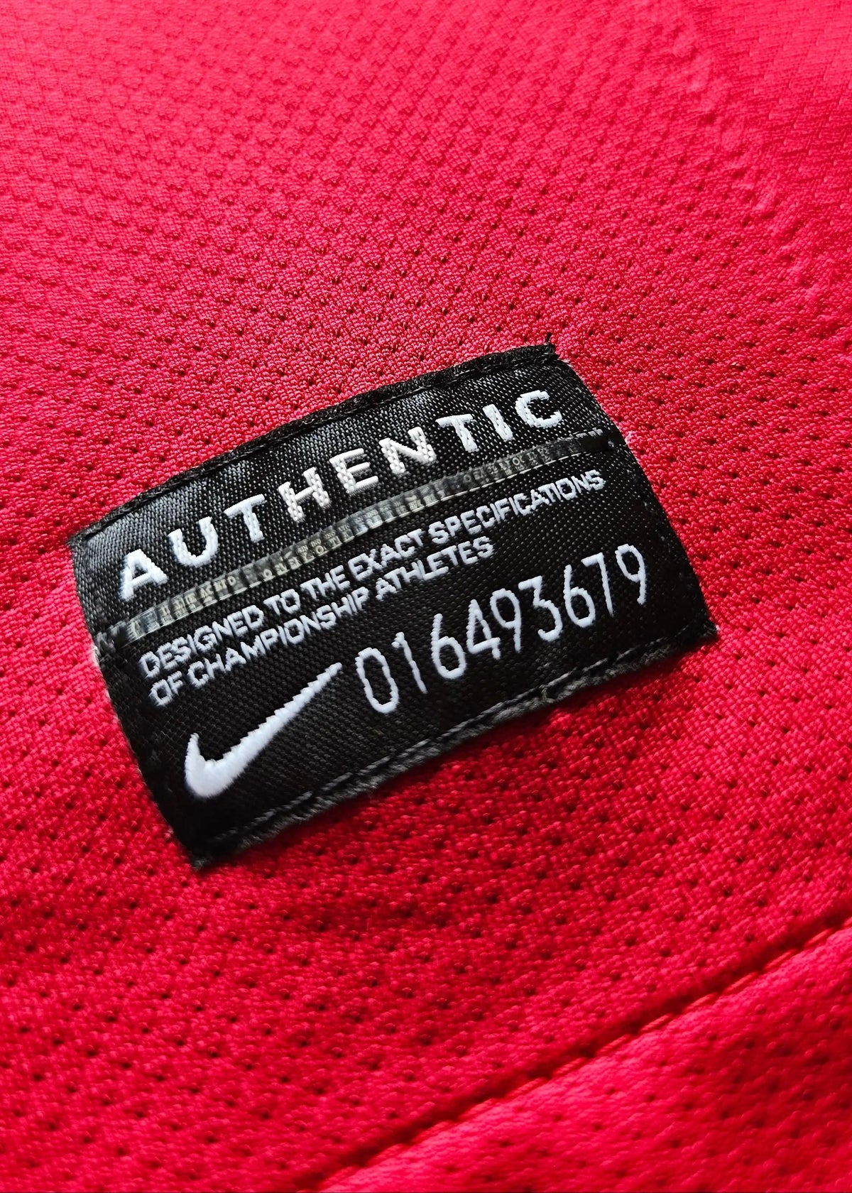 Close-up of an interior AUTHENTIC Nike tag sewn into a red Arsenal shirt, part of Robin van Persie's 2011-12 No. 10 home kit.
