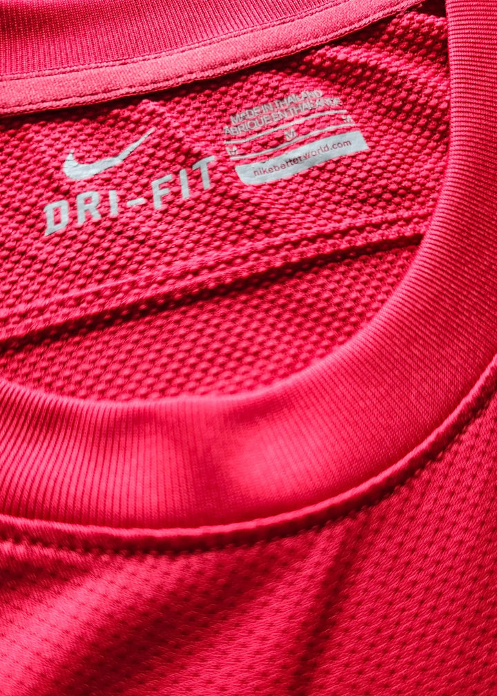 Close-up of the interior collar tag reading DRI-FIT with a Nike swoosh and made-in-Thailand text, inside Robin van Persie's red Arsenal shirt.