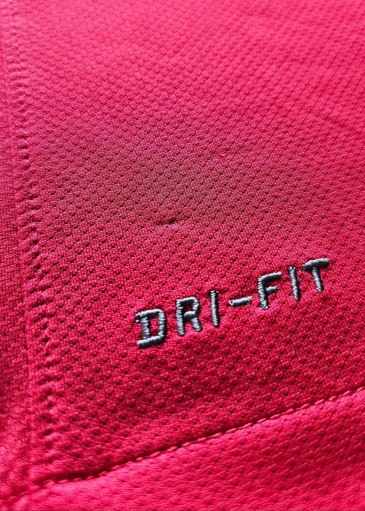 Close-up of the grey DRI-FIT logo embroidered on red fabric, part of Robin van Persie's Arsenal Champions League No. 10 shirt.