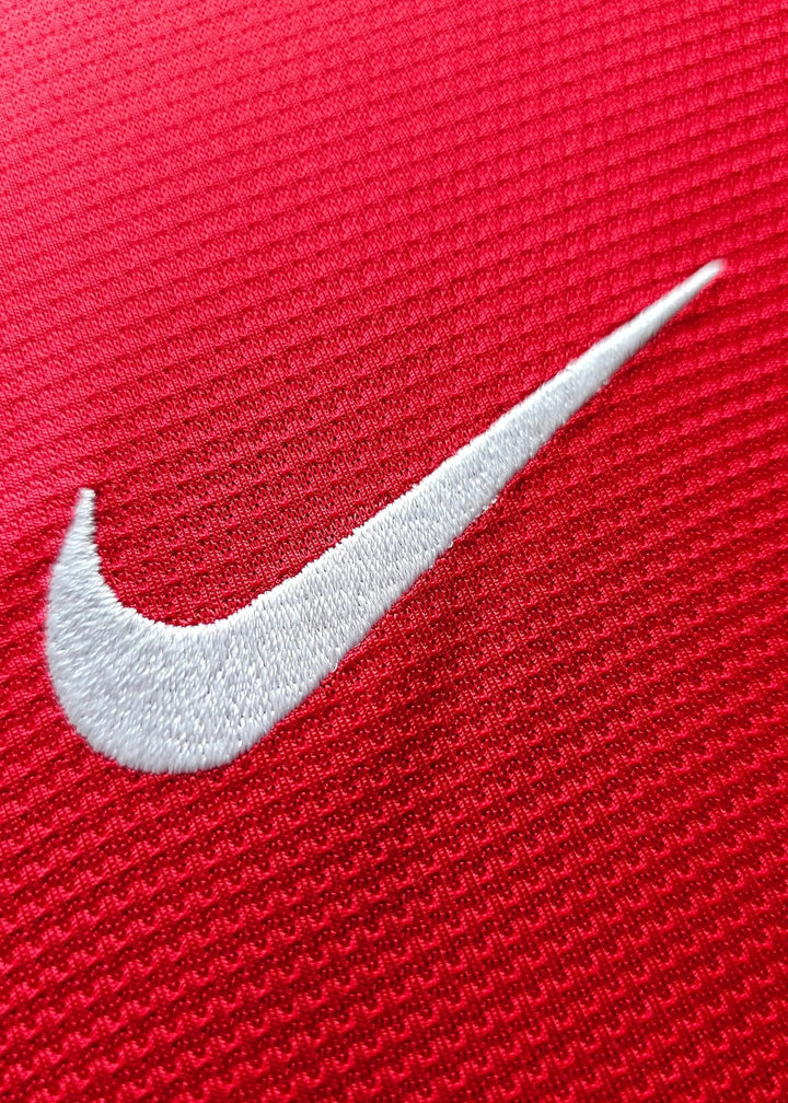 Close-up of the white embroidered Nike swoosh on the red chest, from Robin van Persie's signed Manchester United 2014-15 No. 20 shirt.