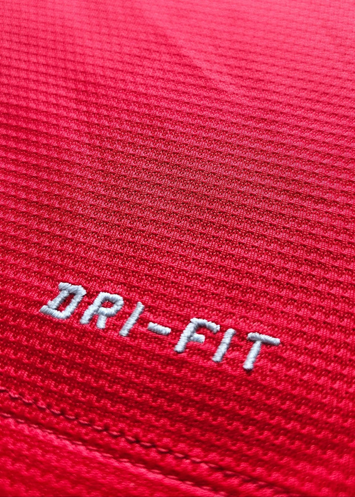 Close-up of the embroidered Nike DRI-FIT tag on the red chest, from Robin van Persie's signed Manchester United 2014-15 No. 20 shirt.