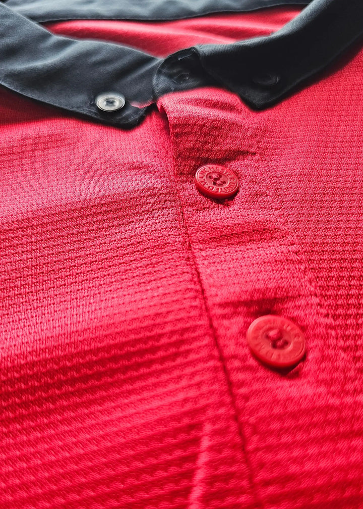 Close-up of red buttons embossed with Manchester United text on the black collar placket, Robin van Persie's signed 2014-15 No. 20 shirt.