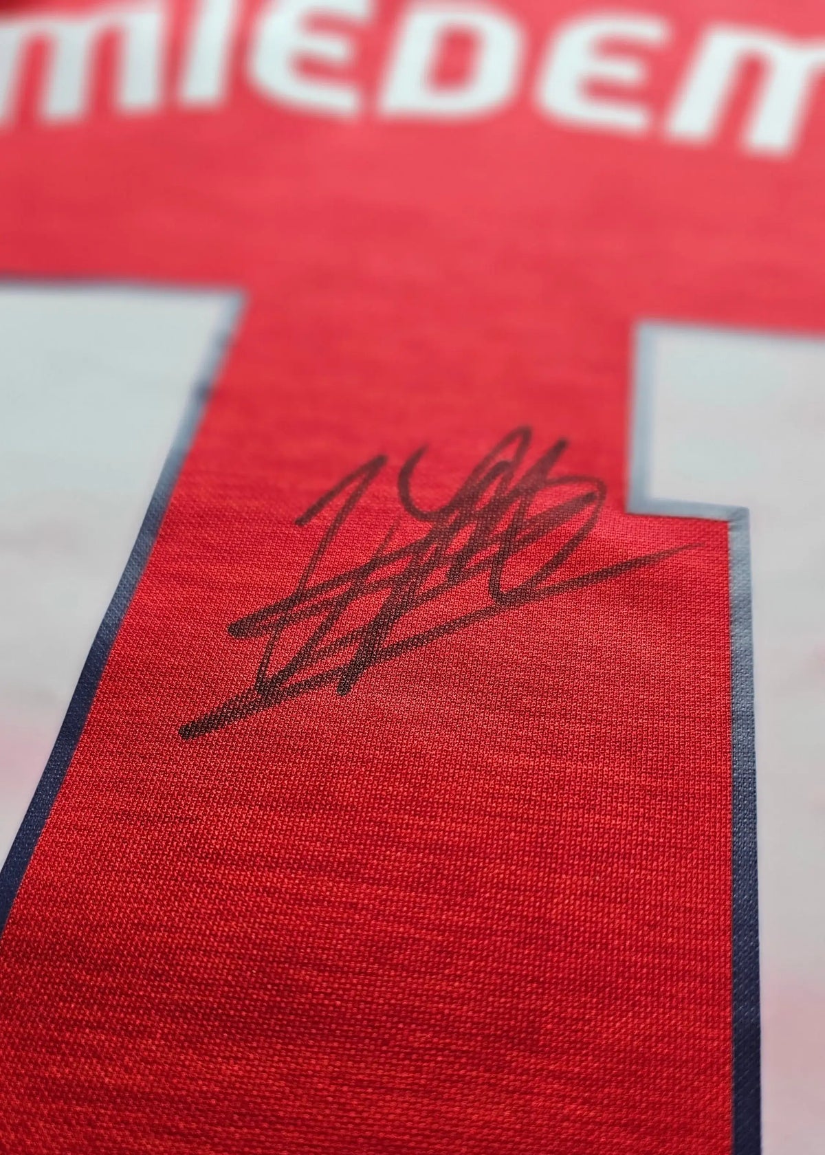 Close-up of the signature on the red football shirt with the name Miedema and No. 11.